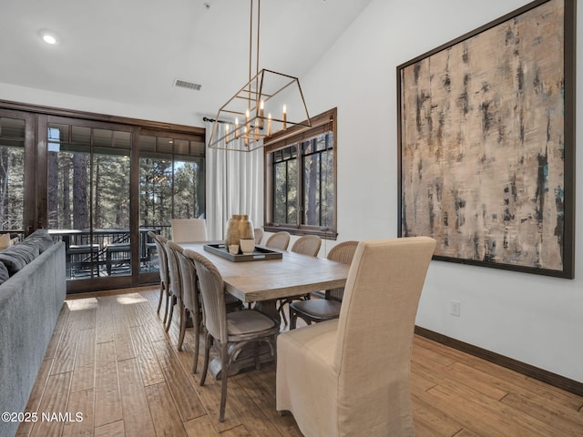 dining room with wood-type flooring, a chandelier, and lofted ceiling