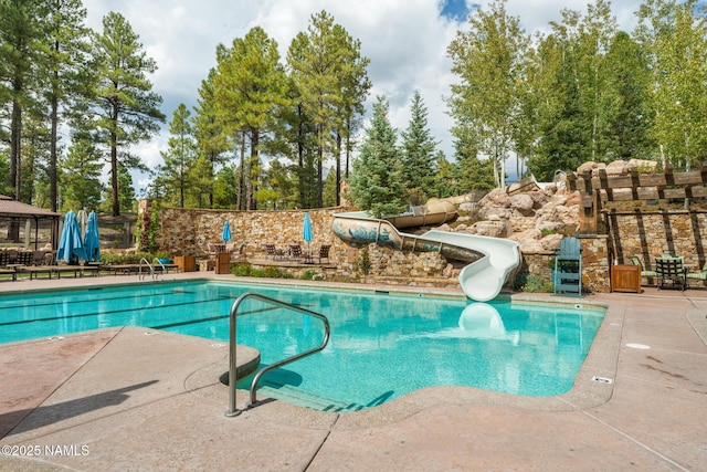 view of swimming pool with a patio area and a water slide