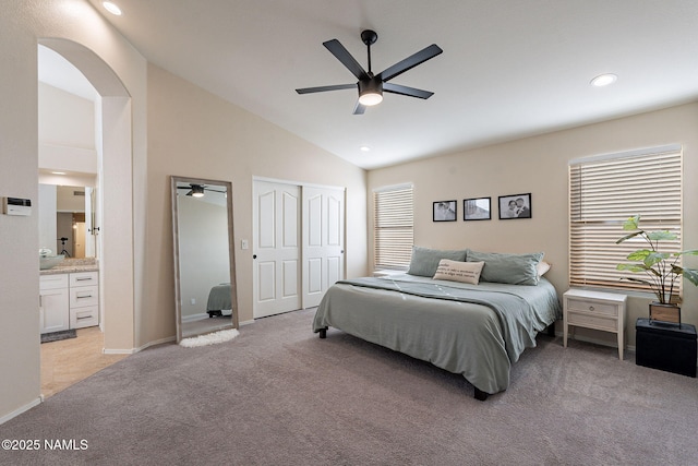 bedroom with lofted ceiling, multiple windows, light carpet, and ensuite bathroom