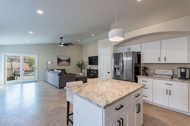 kitchen with pendant lighting, white cabinetry, a center island, light stone countertops, and stainless steel fridge with ice dispenser