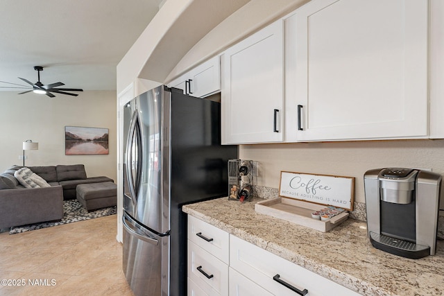 kitchen with light stone counters, light tile patterned floors, stainless steel refrigerator, ceiling fan, and white cabinets