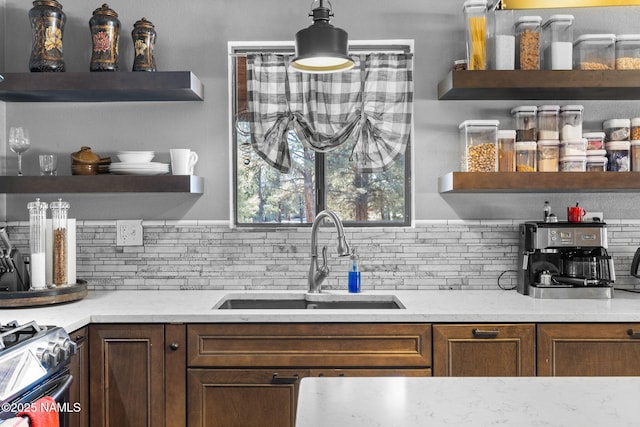 bar with tasteful backsplash, sink, light stone counters, and stainless steel gas range oven