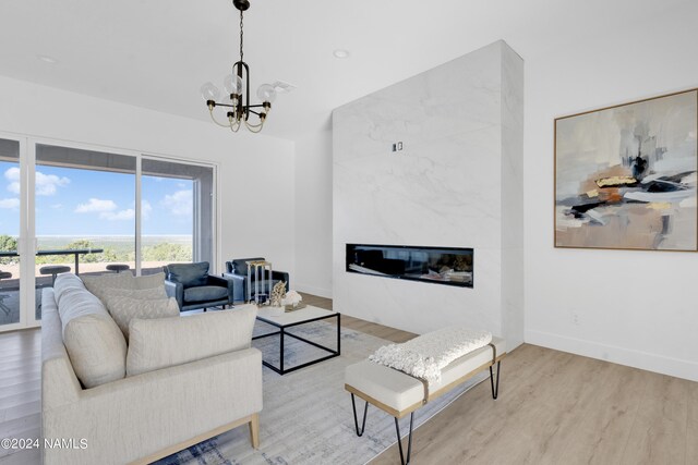 living room featuring light wood-type flooring, an inviting chandelier, and a fireplace