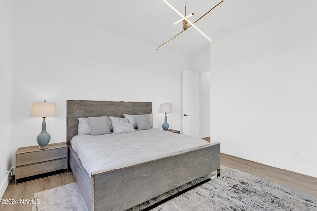 bedroom with light hardwood / wood-style floors and a notable chandelier