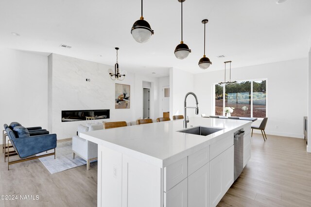 kitchen with dishwasher, white cabinetry, a kitchen island with sink, sink, and pendant lighting