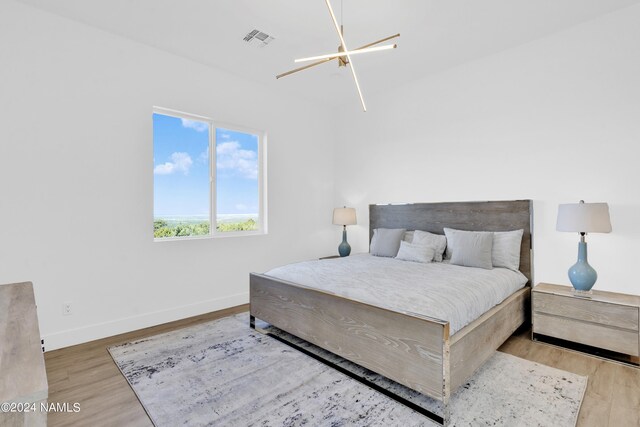 bedroom with a notable chandelier and light wood-type flooring