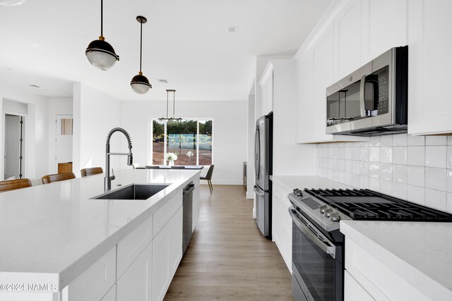 kitchen featuring sink, hanging light fixtures, white cabinets, and stainless steel appliances