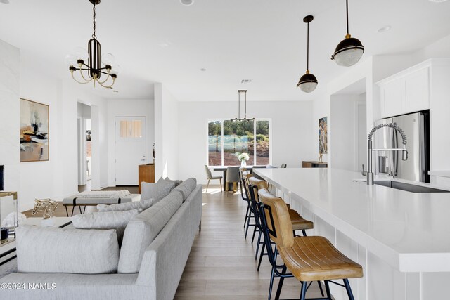 kitchen with decorative light fixtures, sink, white cabinets, a chandelier, and a breakfast bar area