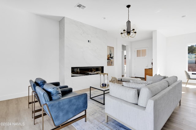 living room featuring a fireplace, light wood-type flooring, and a notable chandelier