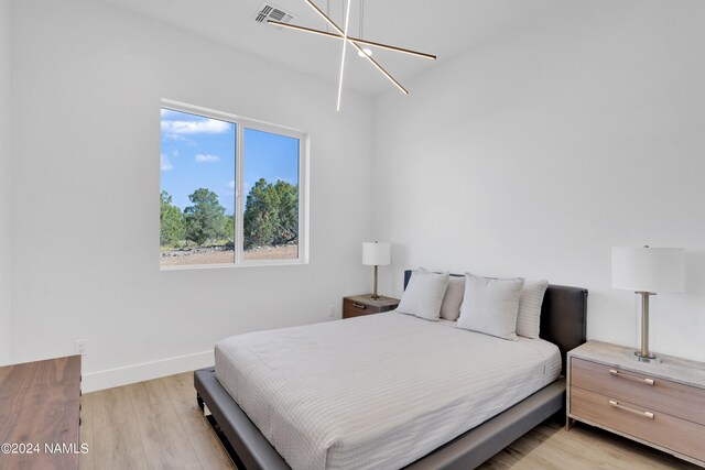 bedroom featuring a notable chandelier and light hardwood / wood-style flooring