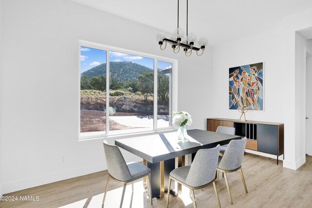 dining area with light hardwood / wood-style floors, a mountain view, and a notable chandelier