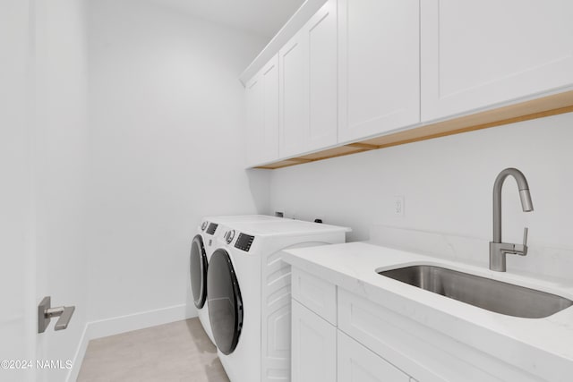 washroom with sink, washing machine and dryer, and cabinets