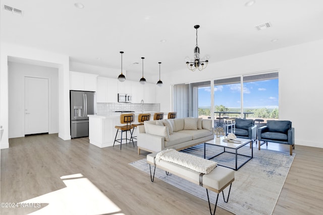 living room with a notable chandelier, light hardwood / wood-style floors, and sink