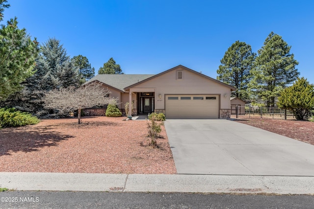 single story home featuring concrete driveway, stone siding, a garage, and fence