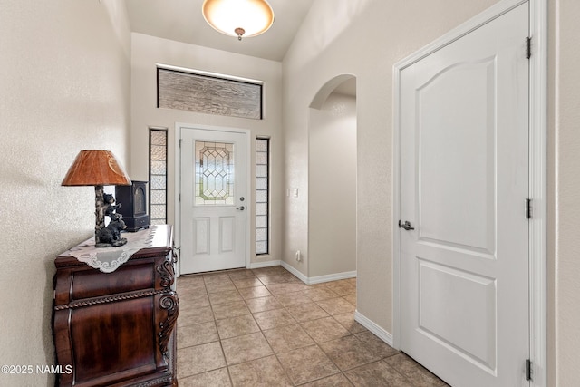 entrance foyer with light tile patterned floors, arched walkways, and baseboards