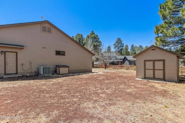 view of property exterior with central AC, fence, an outdoor structure, and a shed
