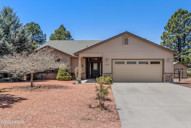 ranch-style house featuring fence, driveway, an attached garage, and stone siding