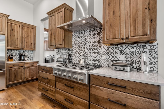 kitchen with wood-type flooring, separate washer and dryer, decorative backsplash, stainless steel appliances, and wall chimney exhaust hood