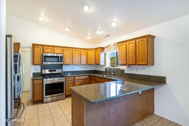 6120 E Treadway Trl, Flagstaff, AZ 86004 - kitchen featuring appliances with stainless steel finishes, a sink, a peninsula, brown cabinetry, and vaulted ceiling
