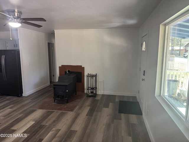 interior space with a wood stove, dark wood-type flooring, and ceiling fan