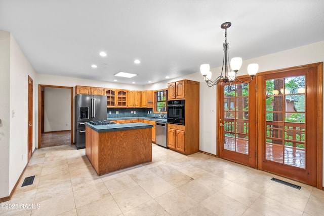3130 Tina Ln, Flagstaff, AZ 86001 - kitchen with stainless steel appliances, a center island, dark countertops, a chandelier, and decorative backsplash