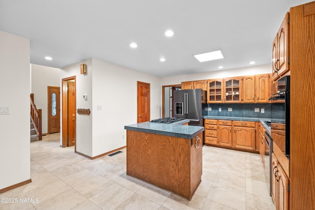 3130 Tina Ln, Flagstaff, AZ 86001 - kitchen with stainless steel appliances, a center island, dark countertops, tasteful backsplash, and glass insert cabinets
