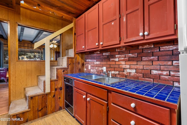 kitchen featuring sink, light wood-type flooring, ceiling fan, and tile counters