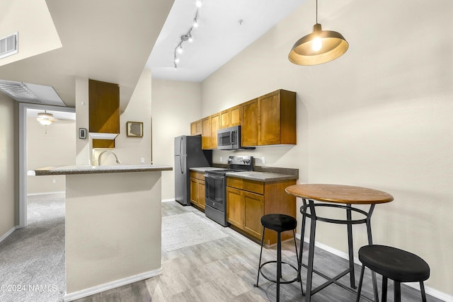 kitchen with a kitchen bar, light hardwood / wood-style floors, track lighting, kitchen peninsula, and stainless steel appliances