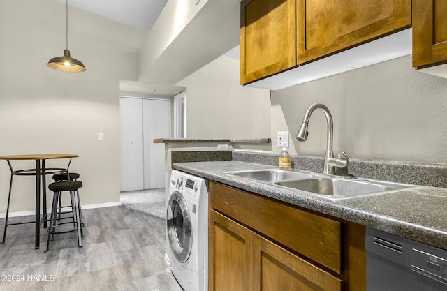 clothes washing area with sink, washer / clothes dryer, and light wood-type flooring