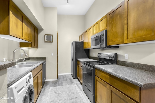 kitchen with sink, washer / clothes dryer, light hardwood / wood-style flooring, and appliances with stainless steel finishes