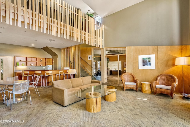 living room with wood walls, carpet, and a high ceiling