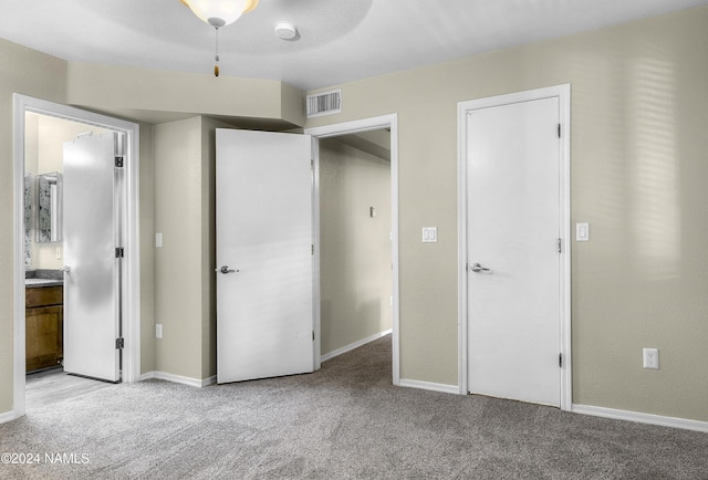 unfurnished bedroom with light colored carpet, connected bathroom, and ceiling fan