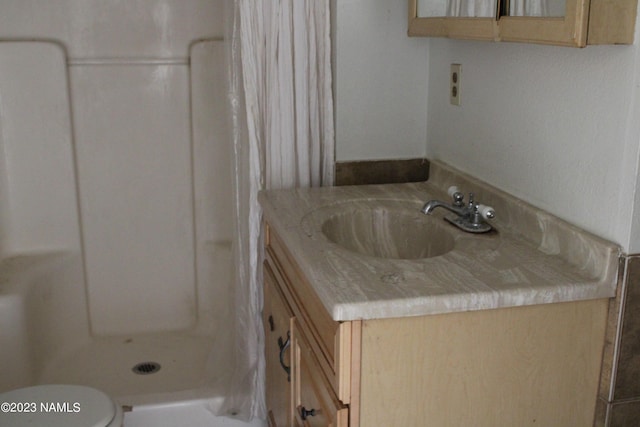 bathroom featuring toilet, a shower with shower curtain, and vanity