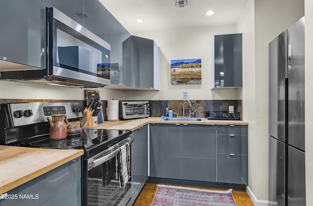 2929 Kletha Trl, Flagstaff, AZ 86005 - kitchen with stainless steel appliances, a sink, butcher block countertops, gray cabinetry, and light wood-style floors