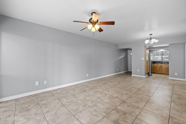 unfurnished living room featuring ceiling fan with notable chandelier, sink, and light tile patterned flooring