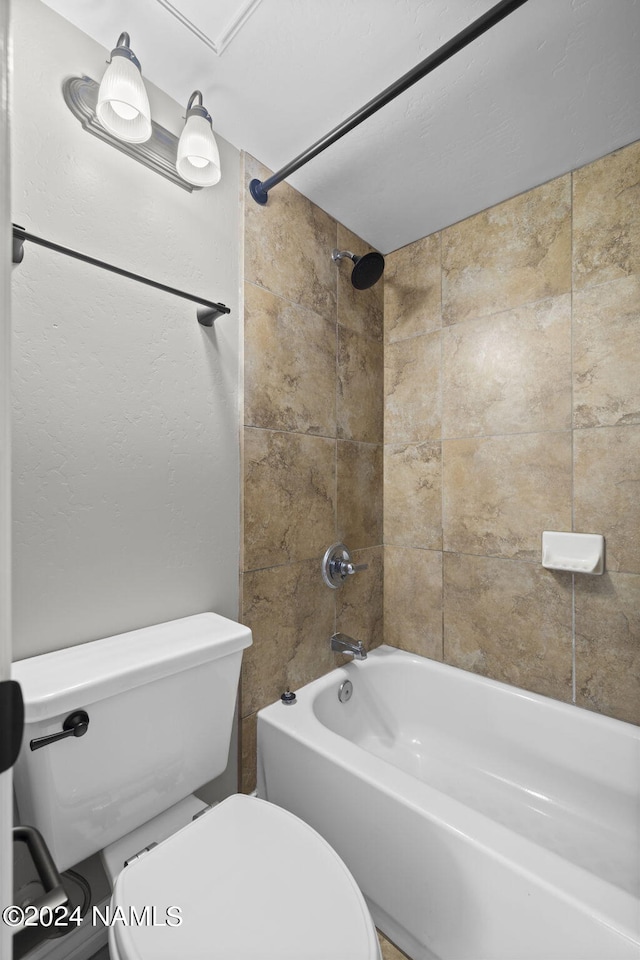 bathroom featuring tiled shower / bath combo and toilet