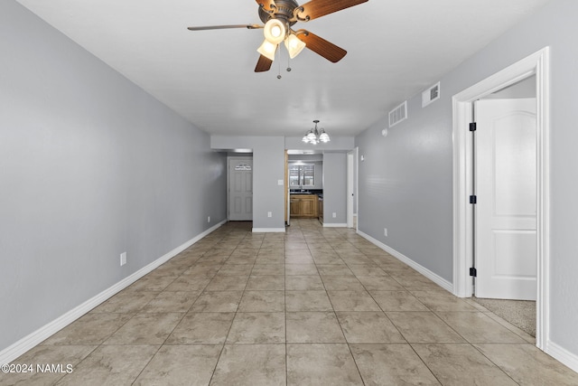 unfurnished living room with ceiling fan with notable chandelier and light tile patterned floors