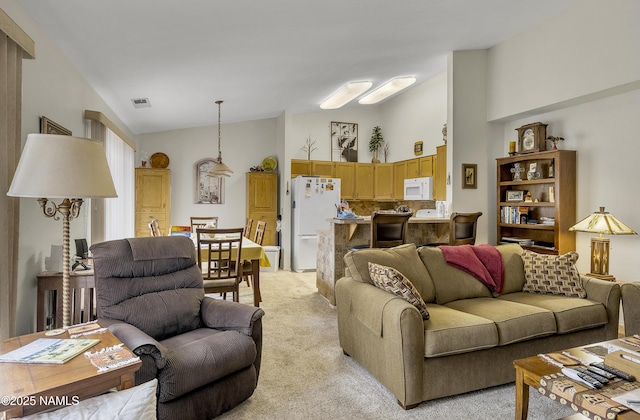 living area with visible vents, light carpet, and vaulted ceiling