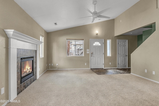 unfurnished living room with visible vents, baseboards, a tiled fireplace, a ceiling fan, and carpet flooring