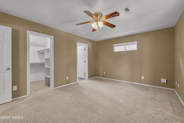 unfurnished bedroom with a walk in closet, visible vents, baseboards, and carpet floors