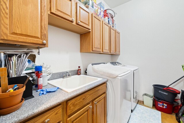 laundry area featuring sink, cabinets, washer and clothes dryer, and light hardwood / wood-style floors