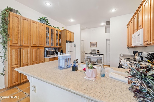 kitchen with light stone counters, white appliances, and light tile patterned flooring