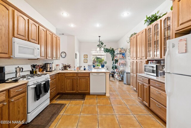 kitchen with white appliances, sink, hanging light fixtures, kitchen peninsula, and light tile patterned floors