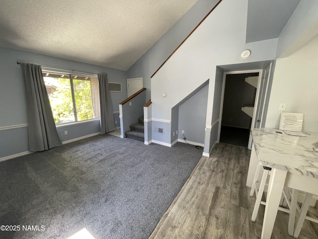1200 S Riordan Ranch St Unit 44, Flagstaff, AZ 86001 - unfurnished living room with vaulted ceiling, stairs, a textured ceiling, and wood finished floors
