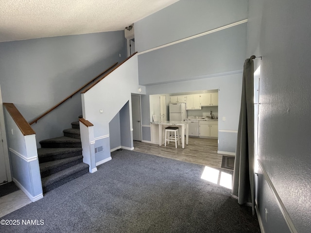 1200 S Riordan Ranch St Unit 44, Flagstaff, AZ 86001 - carpeted living area featuring stairs, high vaulted ceiling, and a textured ceiling