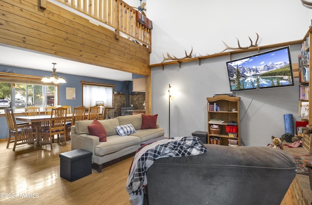 living room with hardwood / wood-style floors, a chandelier, a high ceiling, and a wood stove