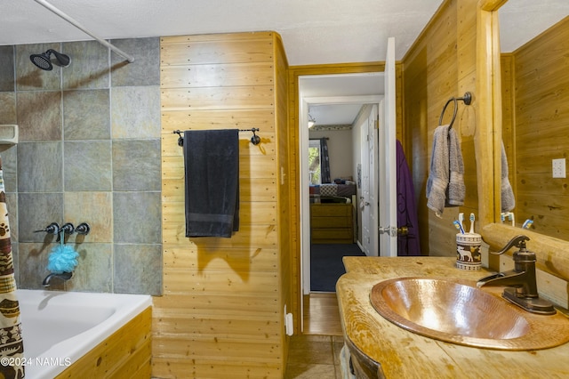 bathroom featuring vanity, wooden walls, tile patterned flooring, and tiled shower / bath combo