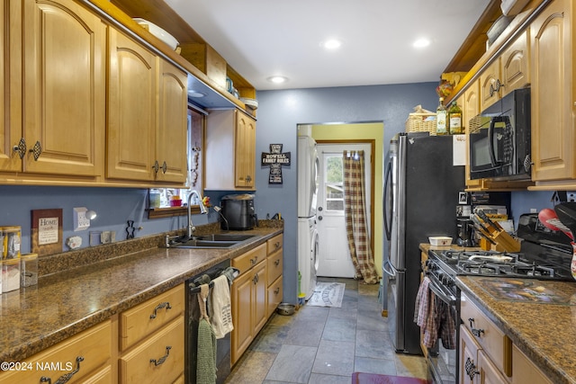 kitchen with black appliances, dark stone counters, and sink