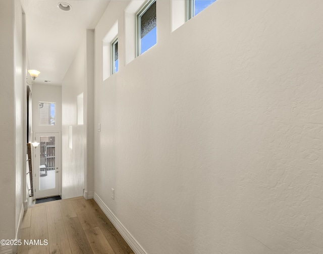 corridor with light wood-style floors and baseboards