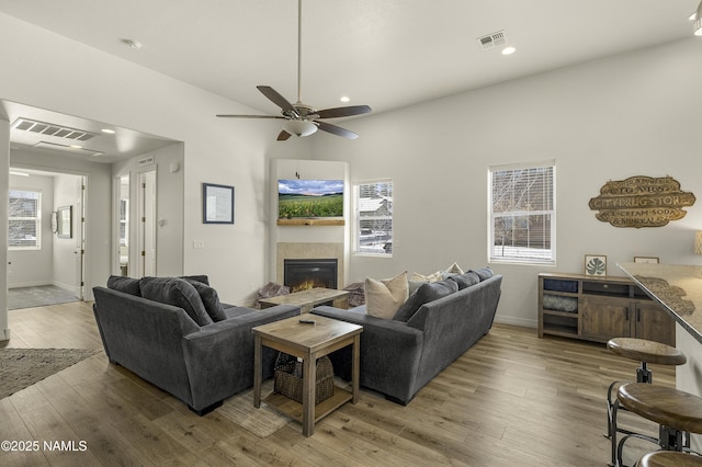 living area with a wealth of natural light, a tile fireplace, visible vents, and wood finished floors